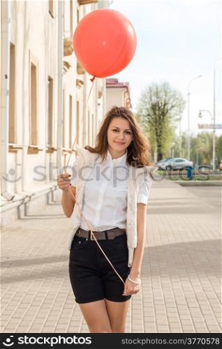 Beautiful fashion girl with red balloon on the empty street of the old town