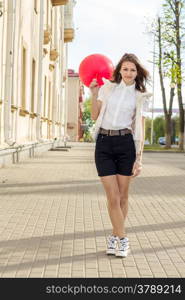 Beautiful fashion girl with red balloon on the empty street of the old town