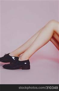 Beautiful fashion model legs wearing shiny shoes on pink background