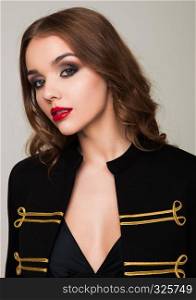 Beautiful fashion model wearing black jacket with golden stripes luxury fancy clothing on grey background