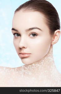 Beautiful fashion model with natural makeup spa skin care portrait on blue bokeh background with shiny glitter stars on neck