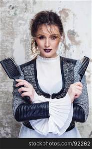 Beautiful fashion portrait of young woman model with sexy dark red lips make-up and wet messy hairstyle holding black comb and hairbrush. Hairstyling concept.