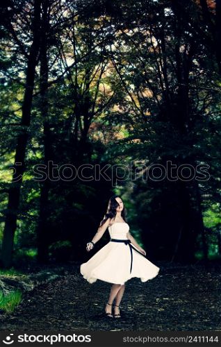 Beautiful fashion woman dancing on the forest surrounded by trees