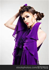 Beautiful fashion woman in purple long dress hairstyle with pigtails design, poses at studio