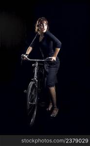 Beautiful fashion woman posing with a old bicycle over a black background