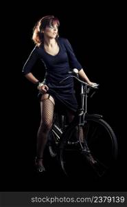 Beautiful fashion woman posing with a old bicycle over a black background