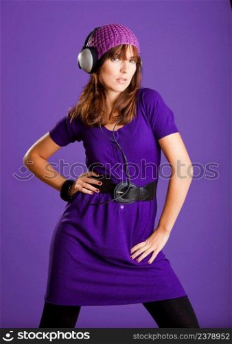 Beautiful fashion young woman listen music with headphones, over a violet background