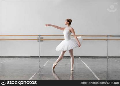 Beautiful female ballet dancer keep the rack in ballet class, barre and white wall on background. Female ballet dancer keep the rack in class