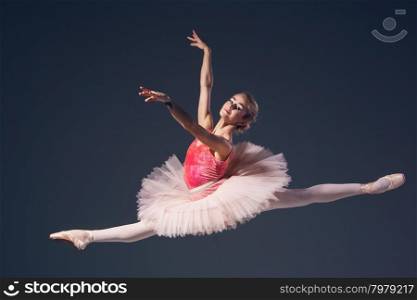 Beautiful female ballet dancer on a grey background. Ballerina is wearing pink tutu and pointe shoes. Beautiful female ballet dancer on a grey background. Ballerina is wearing pink tutu and pointe shoes.