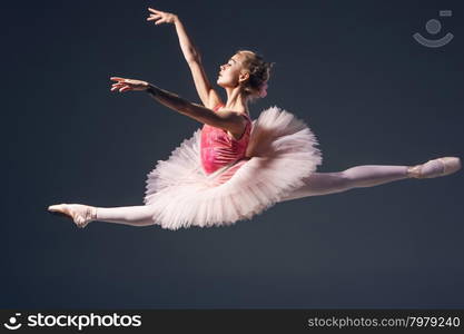 Beautiful female ballet dancer on a grey background. Ballerina is wearing pink tutu and pointe shoes. Beautiful female ballet dancer on a grey background. Ballerina is wearing pink tutu and pointe shoes.