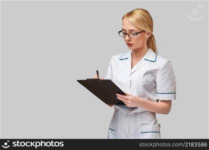 beautiful female doctor holding clipboard isolated on grey background.. beautiful female doctor holding clipboard isolated on grey background
