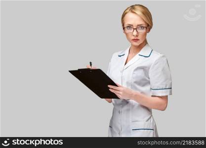 beautiful female doctor holding clipboard isolated on grey background.. beautiful female doctor holding clipboard isolated on grey background