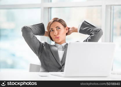 Beautiful female executive relaxing with hands behind head