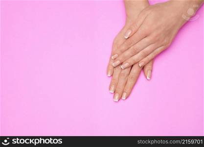 Beautiful Female Hands with French manicure over colorful paper background.. Beautiful Female Hands with French manicure over colorful paper background