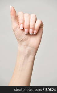 Beautiful Female Hands with French manicure over light grey background.. Beautiful Female Hands with French manicure over light grey background