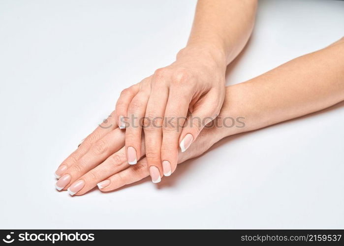 Beautiful Female Hands with French manicure over light grey background.. Beautiful Female Hands with French manicure over light grey background