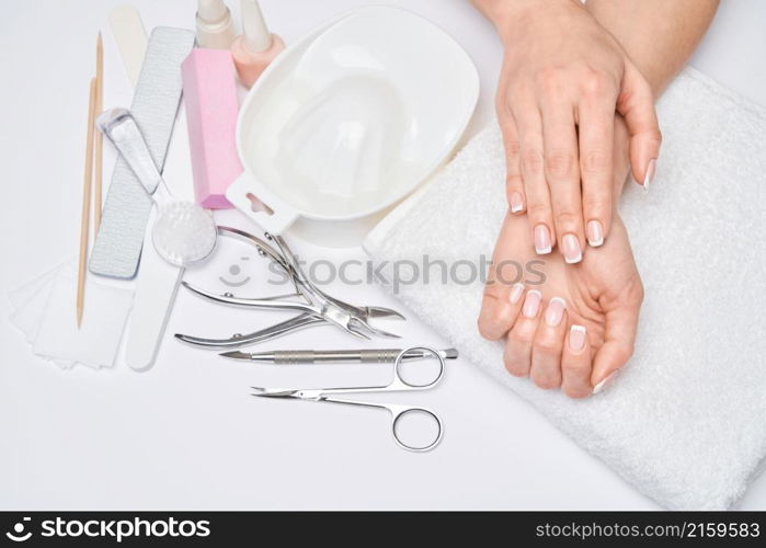 Beautiful Female Hands with French manicure over light grey background.. Beautiful Female Hands with French manicure over light grey background