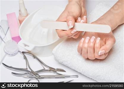 Beautiful Female Hands with French manicure over light grey background.. Beautiful Female Hands with French manicure over light grey background