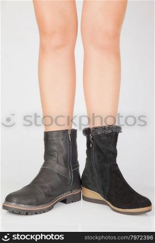 Beautiful female legs in black boots different on a white background