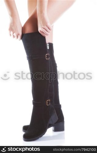 Beautiful female legs in black suede boots on a white background. hand tighten the boots