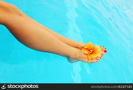 Beautiful female legs in the pool conceptual image of vacation