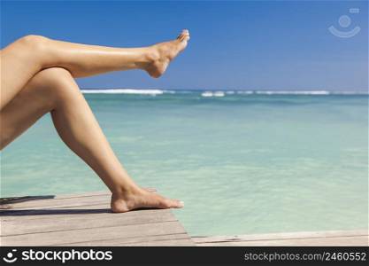 Beautiful female legs with a beautiful tropical beach as background