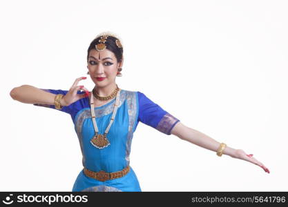 Beautiful female performing classical dance on white background