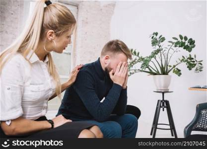 beautiful female psychologist consoling her male depressed patient clinic