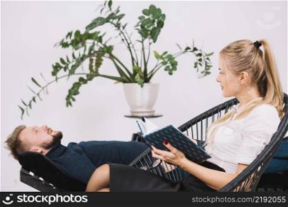 beautiful female psychologist looking male patient lying couch clinic
