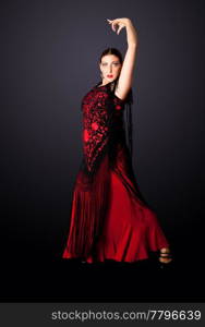 Beautiful female Spanish Flamenco dancer doing a typical line pose, wearing modern attire. Spanish woman dancing Paso Doble in red and black dress clothes, isolated.