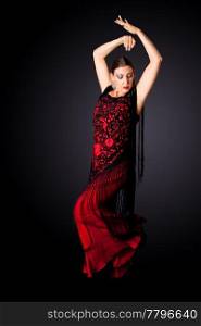 Beautiful female Spanish Flamenco dancer doing a typical line pose, wearing modern attire. Spanish woman dancing Paso Doble in red and black dress clothes, isolated.