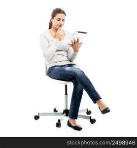 Beautiful female student sitting on a chair with a tablet, isolated over a white background