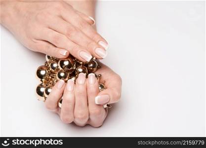 Beautiful Female well-groomed Hands with French manicure holding necklace over light background.. Beautiful Female well-groomed Hands with French manicure holding necklace over light background