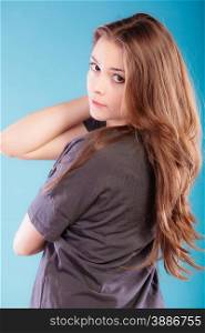Beautiful female young woman teen girl with brown long healthy loose hair blue background