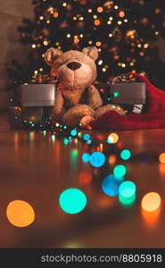 Beautiful Festive Home Interior. Christmas Eve Decoration. Bear with Presents Under Beautiful Xmas Tree Decorated with Colorful Lights. New Year. Magic Christmas Eve at Home