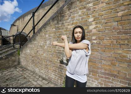 Beautiful fit woman exercising against brick wall