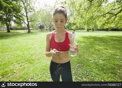 Beautiful fit woman listening to music through cell phone in park