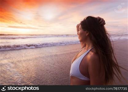 Beautiful fit woman on beach look at sunset time sea summer vacation. Woman in bikini by sea at sunset