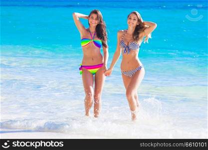 Beautiful fit women in bikni walking on tropical beach. Women walking on beach