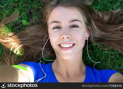 Beautiful fitness girl taking a selfie photo while resting after outdoors workout.