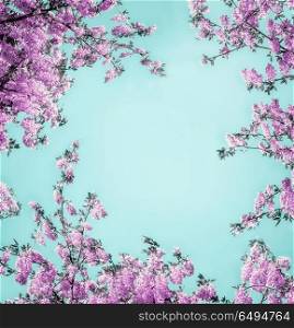 Beautiful floral background with purple lilac blossom on light turquoise, frame. Creative nature flowers layout
