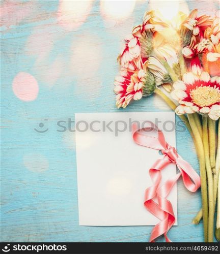 Beautiful flowers bunch with empty greeting card ,ribbon and bokeh on blue shabby chic background, top view