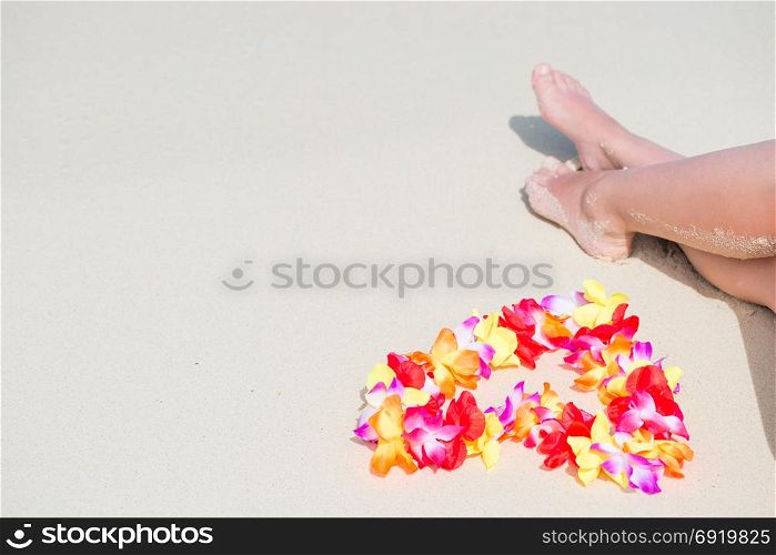 beautiful flowers near female feet on a sandy beach on the ocean in the tropics
