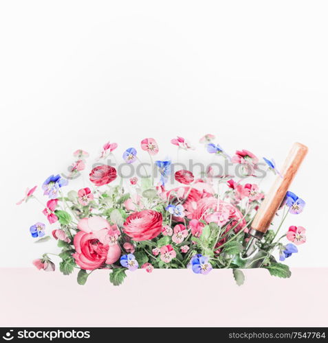 Beautiful flowers with shovel with pink frame at white background. Creative gardening layout. Spring and summer planting concept