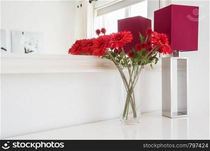 Beautiful flowers with table lamp on white wall background with beautiful mirror modern interior in light house. Beautiful flowers with table lamp on white wall background with beautiful mirror modern interior