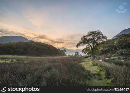 Beautiful foggy misty Fall sunrise over countryside surrounding Crummock Water in Lake District in England