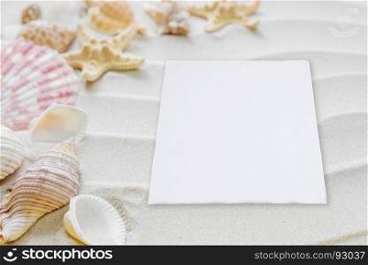 Beautiful frame of clams and starfishes and white paper card on the background of wavy sea sand