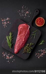 Beautiful freshπece of raw beef on a wooden cutting board on a dark concrete background
