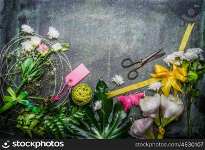Beautiful fresh flowers, pair of scissors and tools to create bouquet on rustic background, top view, border.