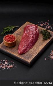 Beautiful fresh piece of raw beef on a wooden cutting board on a dark concrete background